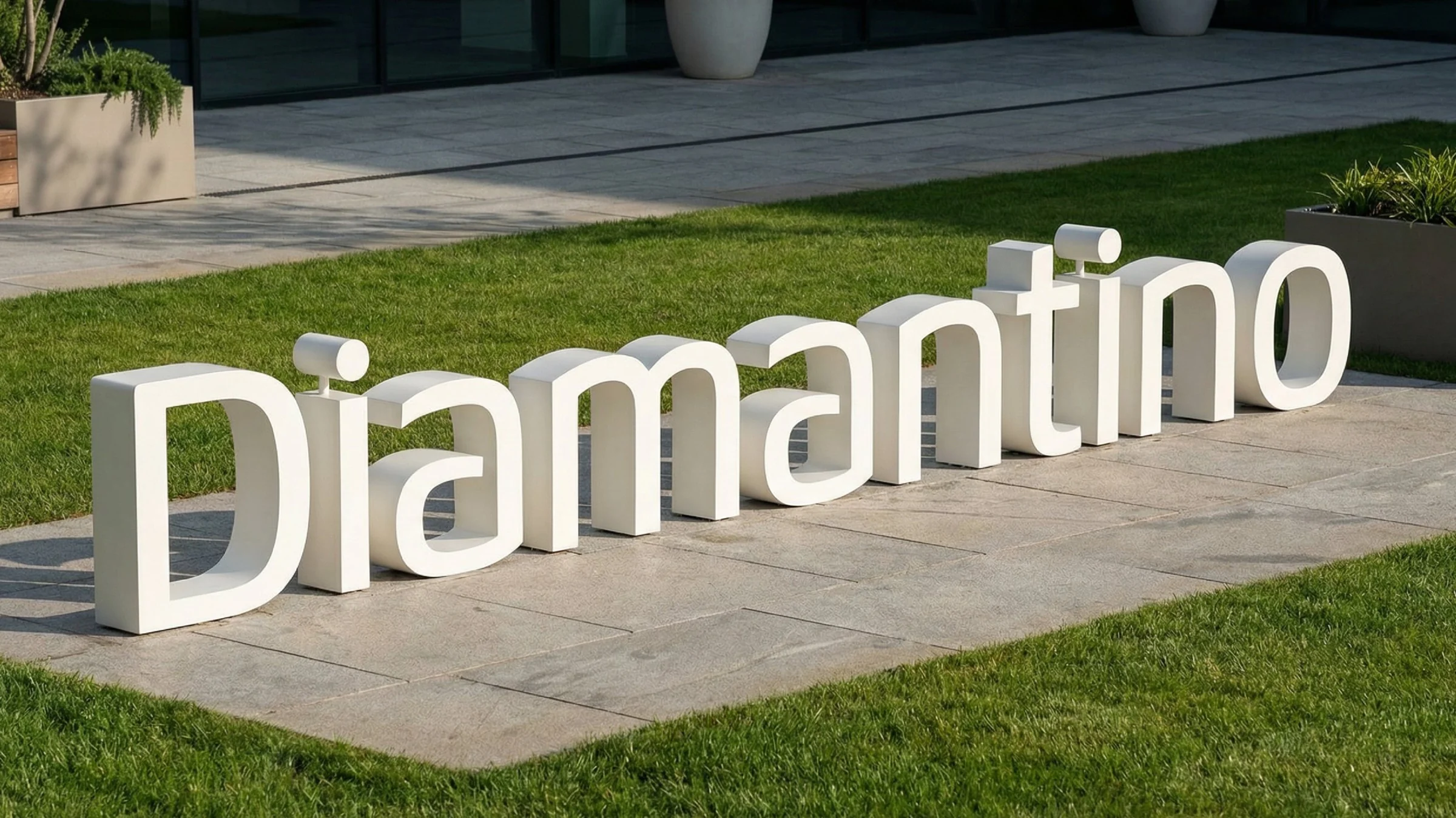 Letras do logotipo Diamantino em volume, brancas, sobre um gramado